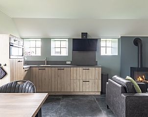 Open keuken en zithoek in De Deel, appartement in Hollum, Ameland, met sfeervolle haard en moderne voorzieningen.