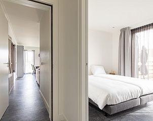 Lichte slaapkamer in De Deel, appartement in Hollum, Ameland, met groot bed en uitzicht op het terras.