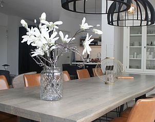 Stijlvolle eetkamer in bungalow Duyngolf 12, Hollum, Ameland. Moderne inrichting met bloemen en sfeervolle verlichting op de Waddeneilanden.