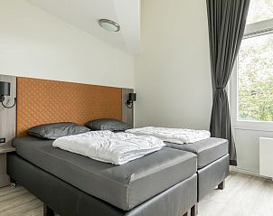 Moderne slaapkamer in Duyngolf 12, een bungalow in Hollum, Ameland, met comfortabel tweepersoonsbed en uitzicht op de natuur.