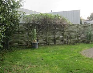 Privacyvolle tuin van Duyngolf 71 vakantiehuis in Hollum Ameland met groene afscheiding.