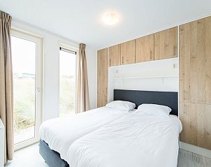 Gezellige slaapkamer in Waddenlodge 6+2, een vakantiehuis in Hollum, Ameland, met houten balken en veel natuurlijk licht.