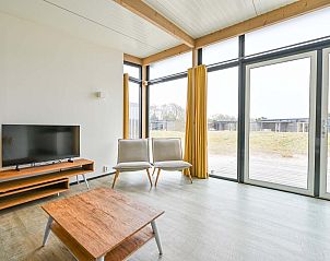 Lichte woonkamer van de vrijstaande woning in Hollum, Ameland, met grote ramen en uitzicht op de Waddeneilanden.