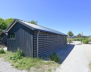 Zijaanzicht van de vrijstaande woning in Hollum, Ameland, omgeven door natuurlijke schoonheid.