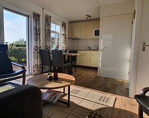 Eetruimte en keuken in Ilsebil vakantiehuis, Hollum, Ameland, met uitzicht op de tuin.