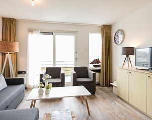 Ruime zithoek in Wad appartement, Hollum, Ameland met moderne inrichting en grote ramen voor natuurlijk licht.