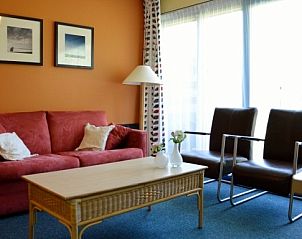 Stijlvolle woonkamer in Appartment Amelander Kaap, Hollum, Ameland met warme kleuren en veel natuurlijk licht.