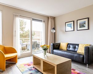 Gezellige woonkamer van appartement Bornrif in Hollum, Ameland met kleurrijk tapijt en comfortabele zitruimte.