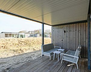 Overdekt terras met zitmeubels bij vakantiewoning in Hollum, Ameland.