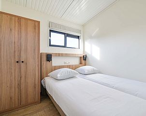 Tweede slaapkamer in vakantiehuis in Hollum, Ameland met houten meubilair.