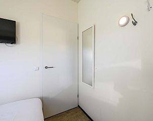 Slaapkamer in vrijstaande woning in Hollum, Ameland met tv en spiegel.