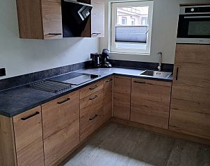 Volledig uitgeruste keuken in vakantiehuis Zeester, Hollum, Ameland, met moderne apparatuur en houten kasten.