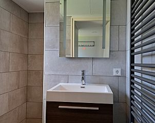 Strakke badkamer in vakantiehuis Zeester, Hollum, Ameland, met moderne wastafel en grote spiegel.