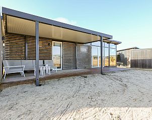 Zijaanzicht van de vrijstaande woning in Hollum, Ameland, vakantieverblijf met houten terras op de Waddeneilanden.
