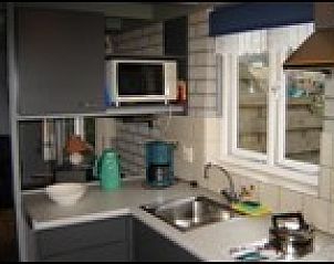 Moderne keuken in vakantiehuis Pirolie, Hollum, Ameland, compleet met apparatuur en uitzicht op de tuin.