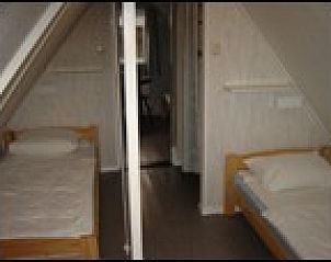 Sfeervolle slaapkamer met twee eenpersoonsbedden in Pirolie, Hollum, Ameland, ideaal voor een ontspannen verblijf.