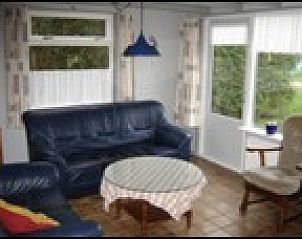 Lichte woonkamer in Pirolie, Hollum, Ameland, met comfortabele zithoek en grote ramen voor veel daglicht.