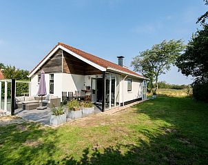 Duinvilla 6 in Hollum, Ameland, Waddeneilanden, biedt een zonnig terras met uitzicht op groene natuur, ideaal vakantiehuis voor ontspanning.