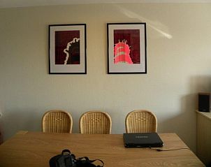 Gemtlicher Innenbereich des Amelander Kaap Nr. 54 in Hollum, Ameland, mit Kunst an der Wand und bequemen Esszimmersthlen.