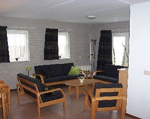 Ruime zitkamer in Freyenburgh, Hollum, Ameland, met moderne meubels, ideaal voor familiebijeenkomsten op de Waddeneilanden.