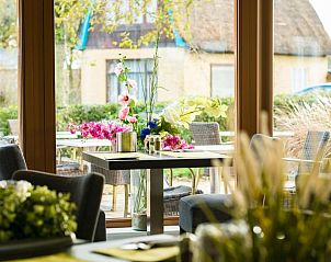 Sfeervolle eetruimte in Hotel Nes, Nes, Ameland, met bloemen en uitzicht op de omgeving.