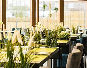 Moderne eetruimte in Hotel Nes, Nes, Ameland, met stijlvolle tafels en groene decoratie.