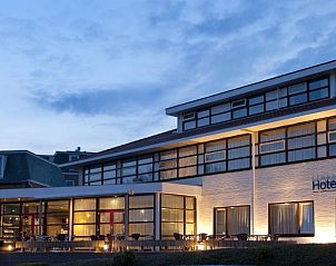 Hotel Ameland in Nes, sfeervol verlicht bij avondschemering.