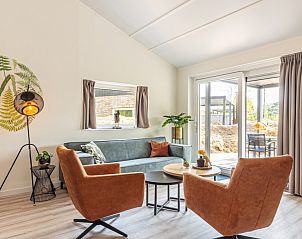 Gezellige woonkamer van Nesserduinen 42A in Nes, Ameland met moderne meubels en toegang tot het terras.