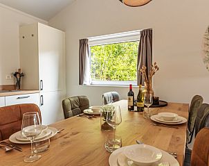 Eettafel in Nesserduinen 42A vakantiehuis in Nes, Ameland met servies en uitzicht op de groene omgeving.