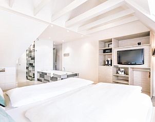 Ruime slaapkamer met televisie in Logement Zee van Tijd, Nes, Ameland.