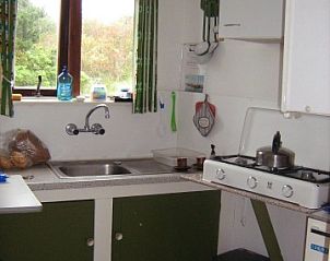 Knusse keuken in De Vijfhoek vakantiehuis, Nes, Ameland, met uitzicht op groene omgeving.
