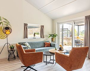 Gemtliche Sitzecke im Ferienhaus in Nes, Ameland, mit viel Tageslicht und Zugang zur Terrasse.