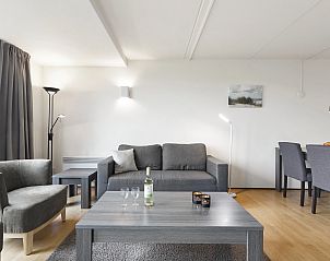 Gemtliche Sitzecke in der Ferienwohnung auf Ameland in Nes, Ameland, mit groem Sofa und Sthlen.