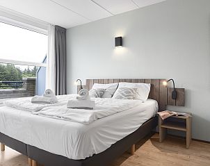 Gerumiges Schlafzimmer mit Doppelbett in Ameland State flat, Nes, Ameland, mit Blick auf den Balkon.