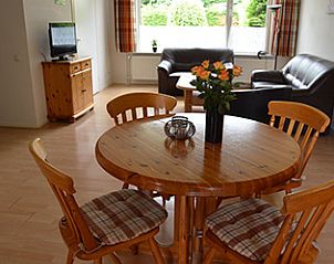 Gezellige woonkamer in Appartementen-Annema in Nes, Ameland, met houten eettafel en comfortabele zithoek voor een ontspannen verblijf.