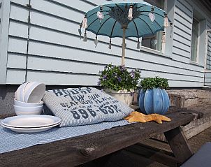 Zonnig terras van Zout bungalow in Buren, Ameland met decoratieve elementen en parasol.