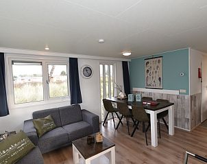 Gezellige binnenruimte van Chalet Zeester in Buren, Ameland, met comfortabele zithoek en eettafel voor een ontspannen verblijf.