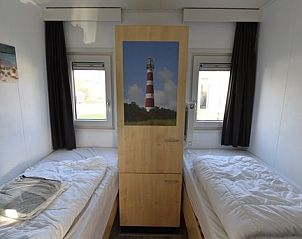 Gezellige slaapkamer in Chalet Zeester, stacaravan in Buren, Ameland, Waddeneilanden, met uitzicht op de vuurtoren en comfortabele bedden.