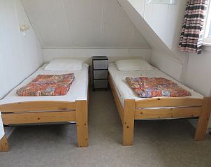 Sfeervolle slaapkamer in vakantiehuis Zeerust, Schiermonnikoog, met comfortabele bedden en gezellige inrichting op de Waddeneilanden.