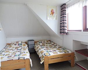 Gezellige slaapkamer in vakantiehuis Zeerust, Schiermonnikoog, met twee eenpersoonsbedden en natuurlijk licht vanuit een groot raam.