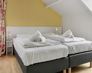 Hoofdslaapkamer in Vitamaris appartement met tweepersoonsbed en kleurrijke accenten op Schiermonnikoog.