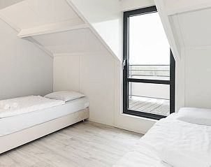 Lichte slaapkamer met eenpersoonsbedden en balkonzicht in Vitamaris appartement op Schiermonnikoog.