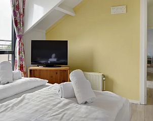 Slaapkamer met tv en balkon in Vitamaris appartement, ideaal voor ontspanning op Schiermonnikoog.