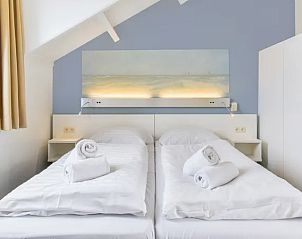 Slaapkamer met tweepersoonsbed en kunst in Vitamaris appartement, Schiermonnikoog, Waddeneilanden.