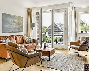 Lichte woonkamer met balkon in Vitamaris appartement, Schiermonnikoog, ideaal voor ontspanning.
