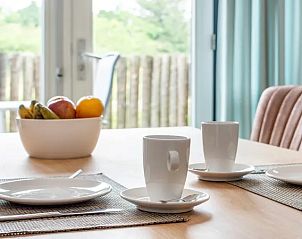 Ontbijttafel met uitzicht op tuin in Vitamaris appartement, Schiermonnikoog, voor een rustige ochtend.