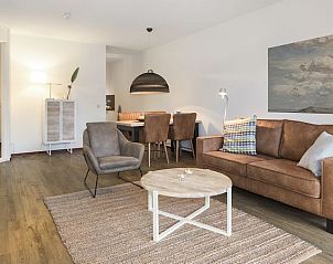 Sfeervolle woonkamer in Vitamaris appartement, Schiermonnikoog, met comfortabele bank en decor.