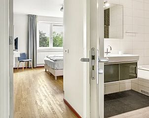 Badkamer met ligbad en wastafel in Vitamaris appartement, Schiermonnikoog, voor ontspanning.