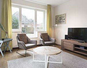 Stijlvolle woonruimte in Vitamaris 4-persoons appartement 4L2, Schiermonnikoog, met grote ramen en comfortabele stoelen.