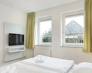 Slaapkamer met uitzicht in Vitamaris 4-persoons appartement 4L2, Schiermonnikoog, uitgerust met een flatscreen tv.